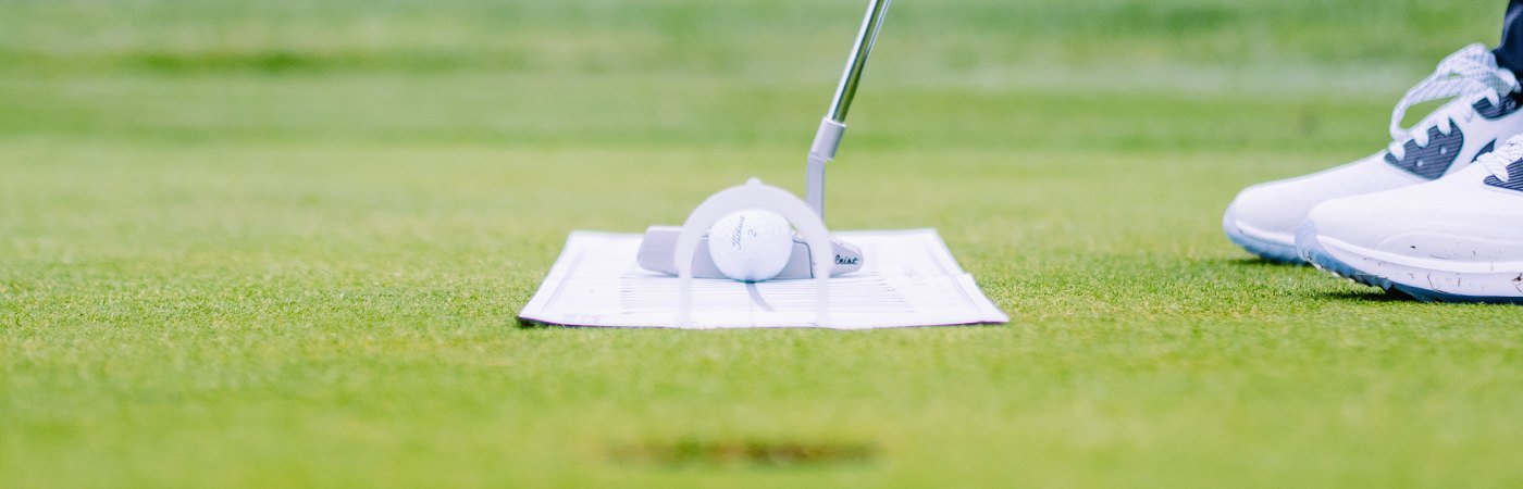 Close-up of a ball in a narrow ball gate, putter behind it